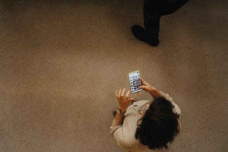 Businesswoman checking phone while standing at the office. Top view, high angle photo.