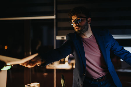 Young team collaborating late at night, analyzing statistics, discussing project details, and developing a marketing strategy for business growth.の写真素材