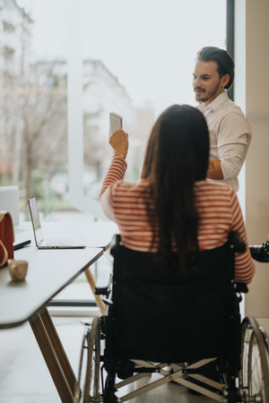 Inclusive workplace with man standing by woman in wheelchair holding noteの写真素材