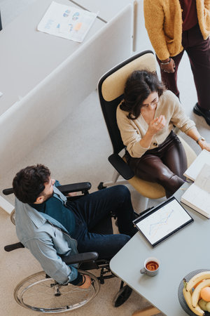 Inclusive team meeting between woman and man in a wheelchair, analytics discussion.