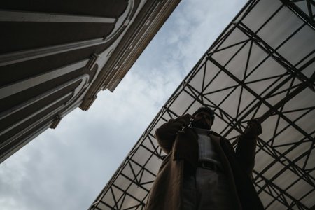 Urban professional talking on smart phone under architectural canopy.の写真素材