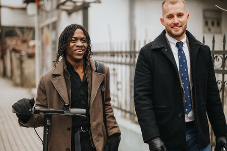 Multiracial business partners walking with scooter and smiling in urban setting.