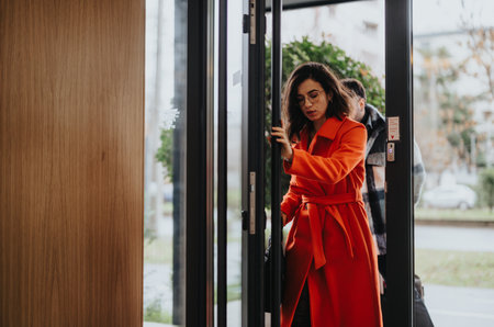 Two colleagues in a candid moment, engaging in conversation as they step in a modern building into a...