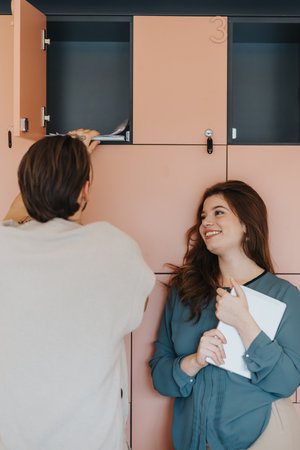 Young colleagues collaborating, discussing ideas, and searching for documentation in office lockers. Positive atmosphere, and teamwork to success.の写真素材