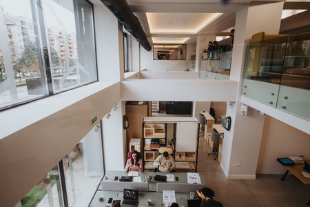 Overhead view of a contemporary, bright office environment where focused individuals collaborate and...