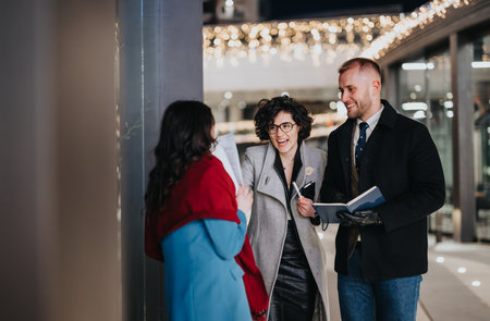 Confident business associates share a light-hearted moment against a backdrop of urban lights and shops during an evening meeting.の写真素材