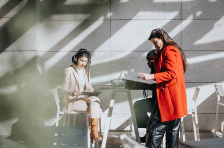 Mixed race business teammates women engaged in creative work process at sunlit table.の写真素材