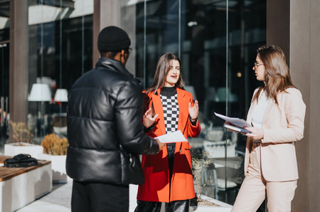 Multiracial business team engaging in a friendly discussion outside office building.の写真素材