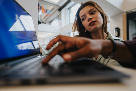 Close-up of a concentrated female employee using a laptop at her workplace. The focus on productivity and technology in a corporate setting.の写真素材