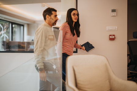 Two professionals walking through office space discussing work.