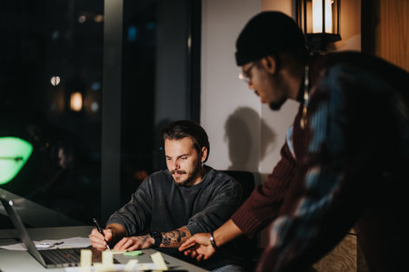 Multicultural business colleagues in deep discussion at evening office meeting.の写真素材
