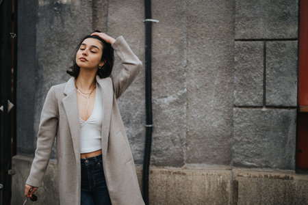 A fashionable young girl with a relaxed demeanor explores the city streets on an autumn day, showcasing contemporary youth style.の写真素材