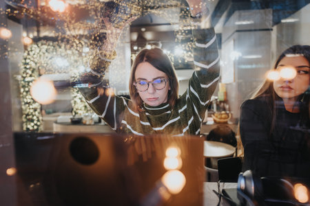 Two diligent young adults collaborate into the night at an office, with city lights creating a...