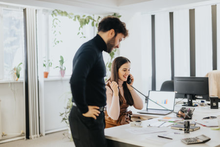 Professional man and woman in office setting, woman on phone call, teamwork and communication concept.の写真素材