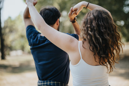 Gorgeous girl teaching her boyfriend how to dance while having fun in the park on a sunny day.の写真素材