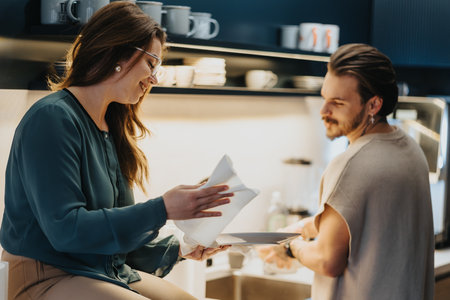 Colleagues enjoying a positive atmosphere in the office kitchen, smiling and discussing together while washing dishes and cleaning.の写真素材
