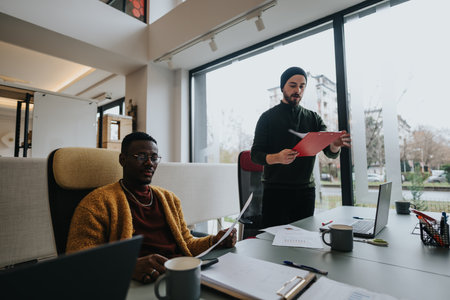 Multiethnic business employees discussing work strategies in a modern office setting.の写真素材