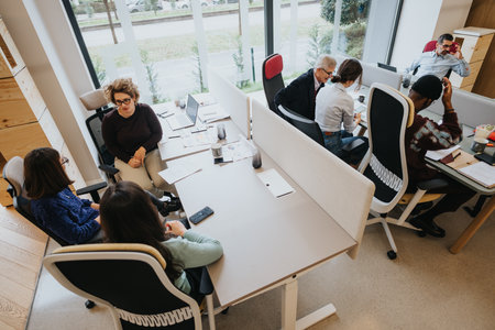 Multiracial group of professionals engaged in a business meeting at a modern office, working together with documents, laptops, and smart phones.の写真素材