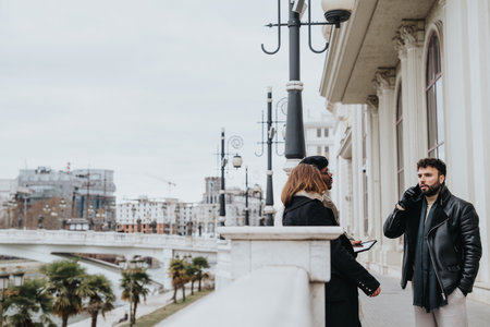 A men and woman engage in conversation on a bridge, showcasing urban street fashion against a...