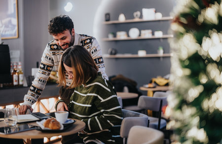 A young man and woman collaborating with enthusiasm in a cozy office environment, with cheerful string lights in the background.の写真素材