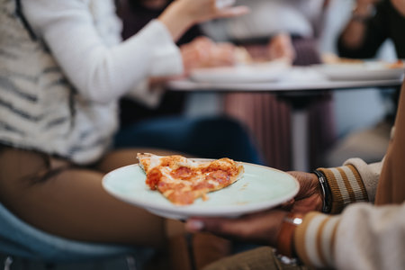 A male person is holding a plate with a slice of pizza on it. Close up photo.の写真素材