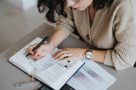Woman writing stats or project notes down in a notebook.の写真素材