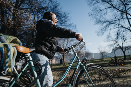 Happy woman enjoying a leisurely bike ride in urban park setting.