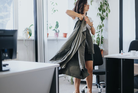 Confident businesswoman getting ready for work, dressing in stylish outfit in modern office environmentの写真素材