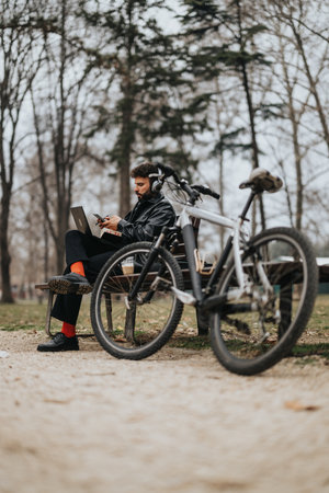 Stylish businessman working remotely in a park with bicycle.
