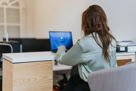 Junior, female employee starting to work on lap top early in the morning.の写真素材