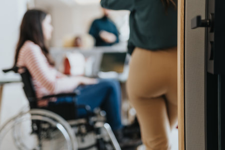 Handicapped, brunette woman in wheelchair cooperating with her coworkers on a new project at the...