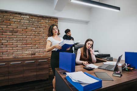 Professional team in modern office: Focused women working and collaborating, busy business environment.の写真素材