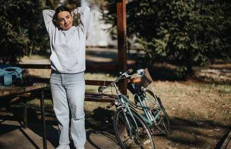 Casual young woman enjoying break on park bench by her bicycleの写真素材