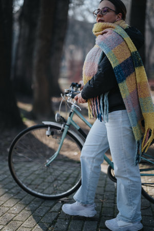 Stylish woman with bicycle enjoying a leisurely day in the park.の写真素材
