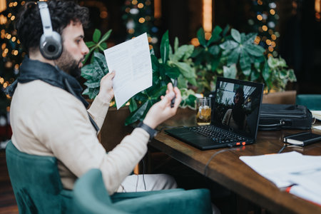 Focused business man with headphones reviewing documents in cozy cafe setting.