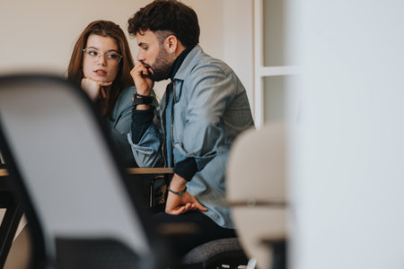 Focused colleagues discussing work project on computer in office