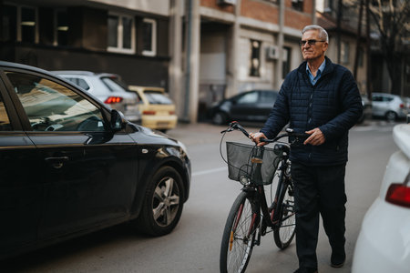 Active elderly gentleman enjoys a healthy lifestyle, posing with his bike on an urban road,...