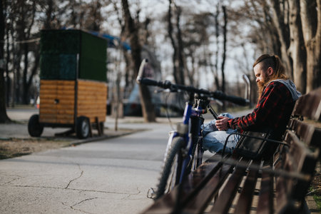 Urban businessman with bicycle checking smart phone, remote work concept