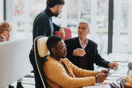 Multi generational, mixed race business colleagues engaged in a discussion at the office.の写真素材