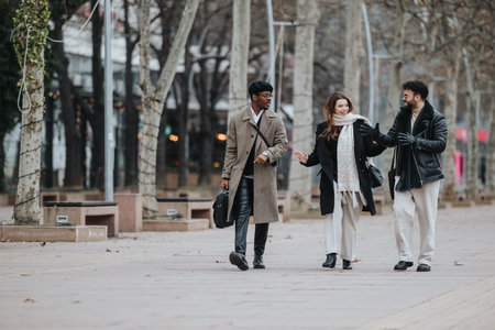 Three young business professionals engaging in a meeting while walking confidently through an urban city setting, embodying remote work dynamics.の写真素材