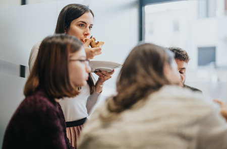 Diverse employees enjoying a lunch break, discussing business and eating pizza. Relaxed and successful atmosphere.の写真素材
