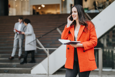 Confident businesswoman on phone with colleagues in backgroundの写真素材