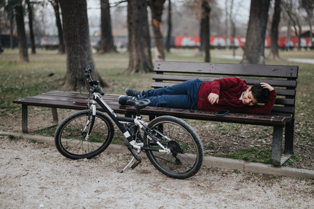 Young boy takes a joyful break in the park with his bicycleの写真素材