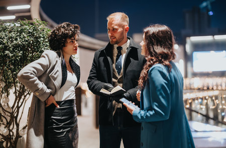 Business teammates engaged in conversation outdoors at night, business networking event.