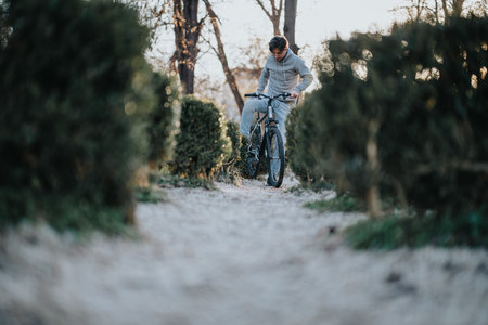 Active man enjoying a bike ride in a leafy park at sunset