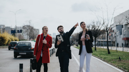 Business colleagues walking together outdoors with coffee and tabletの写真素材