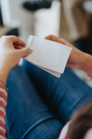 In a close-up photo, a woman meticulously writes notes in her notebook, capturing details.の写真素材