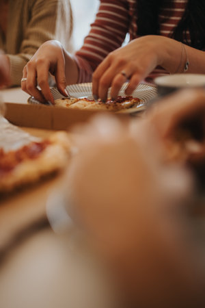 Close-up view of a pizza in a box being shared by friends at an indoor gathering, highlighting the...