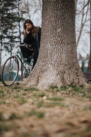 Elegant young businesswoman with her bicycle in an urban parkの写真素材