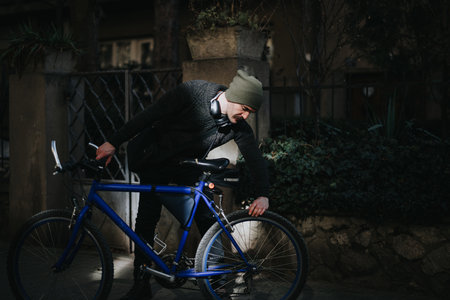Urban cyclist in casual wear checking bicycle on a sunny dayの写真素材
